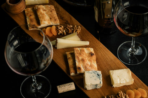 Weingläser und Käseplatte auf Holztisch – welcher Wein passt zu welchem Käse